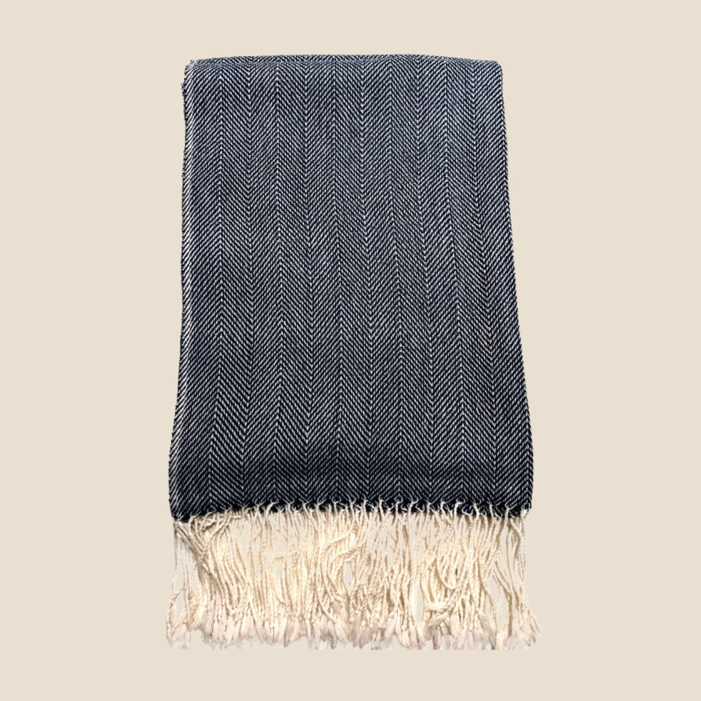Blue woven blanket with white fringe on a beige background