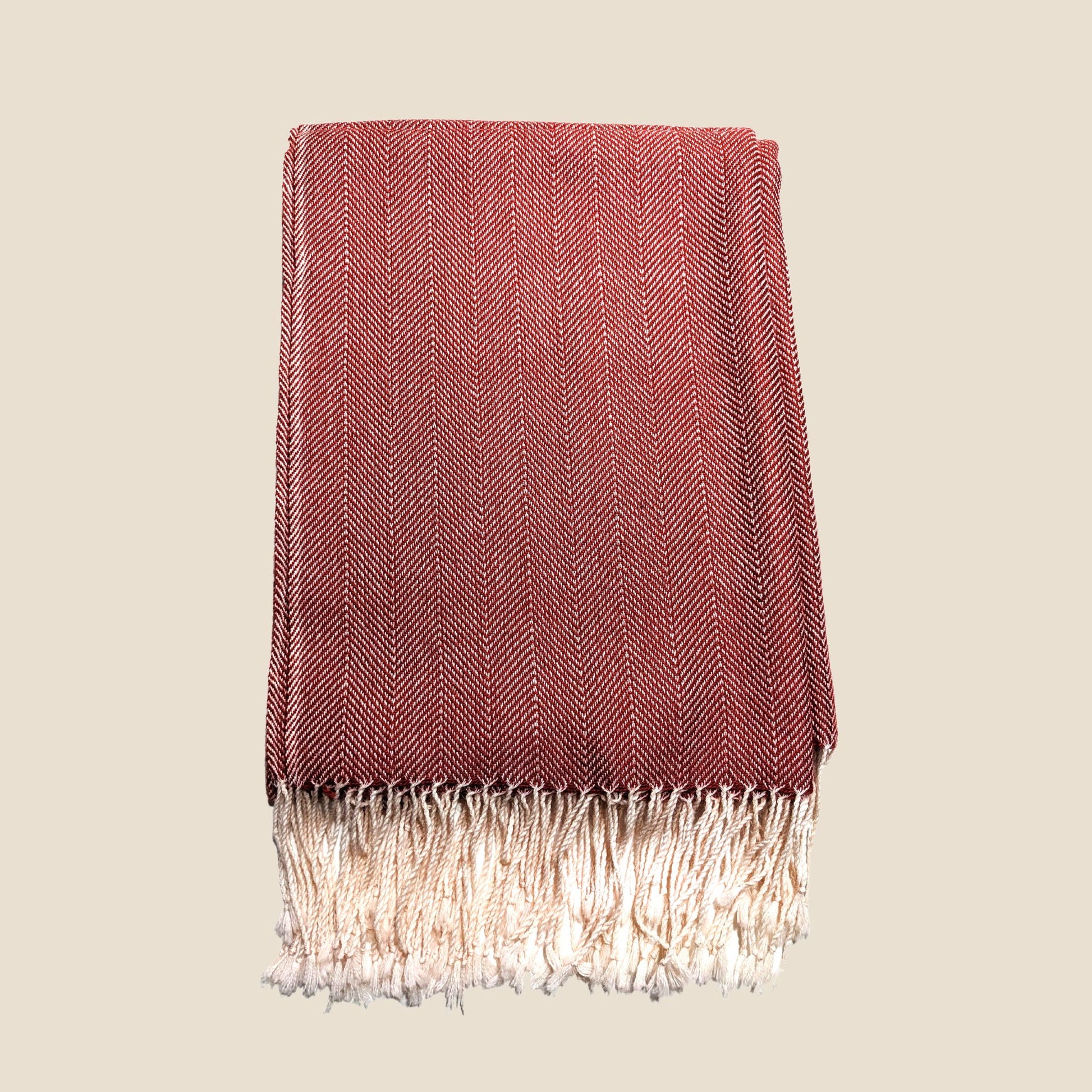 Red woven blanket with fringes on a beige background