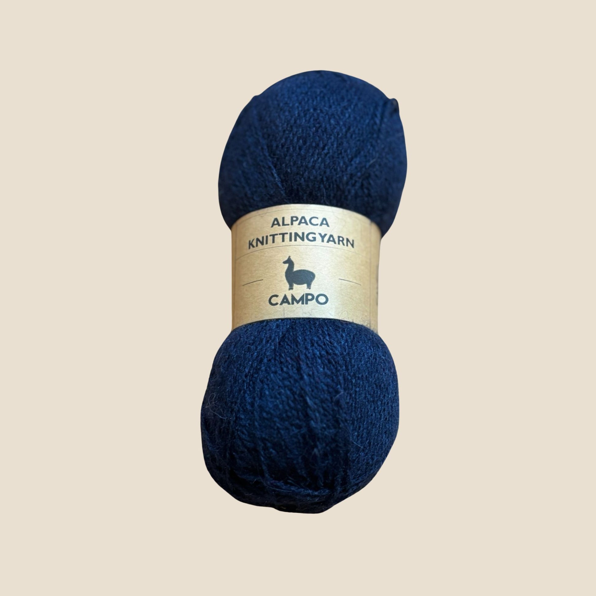 Navy blue alpaca knitting yarn with a label on a beige background