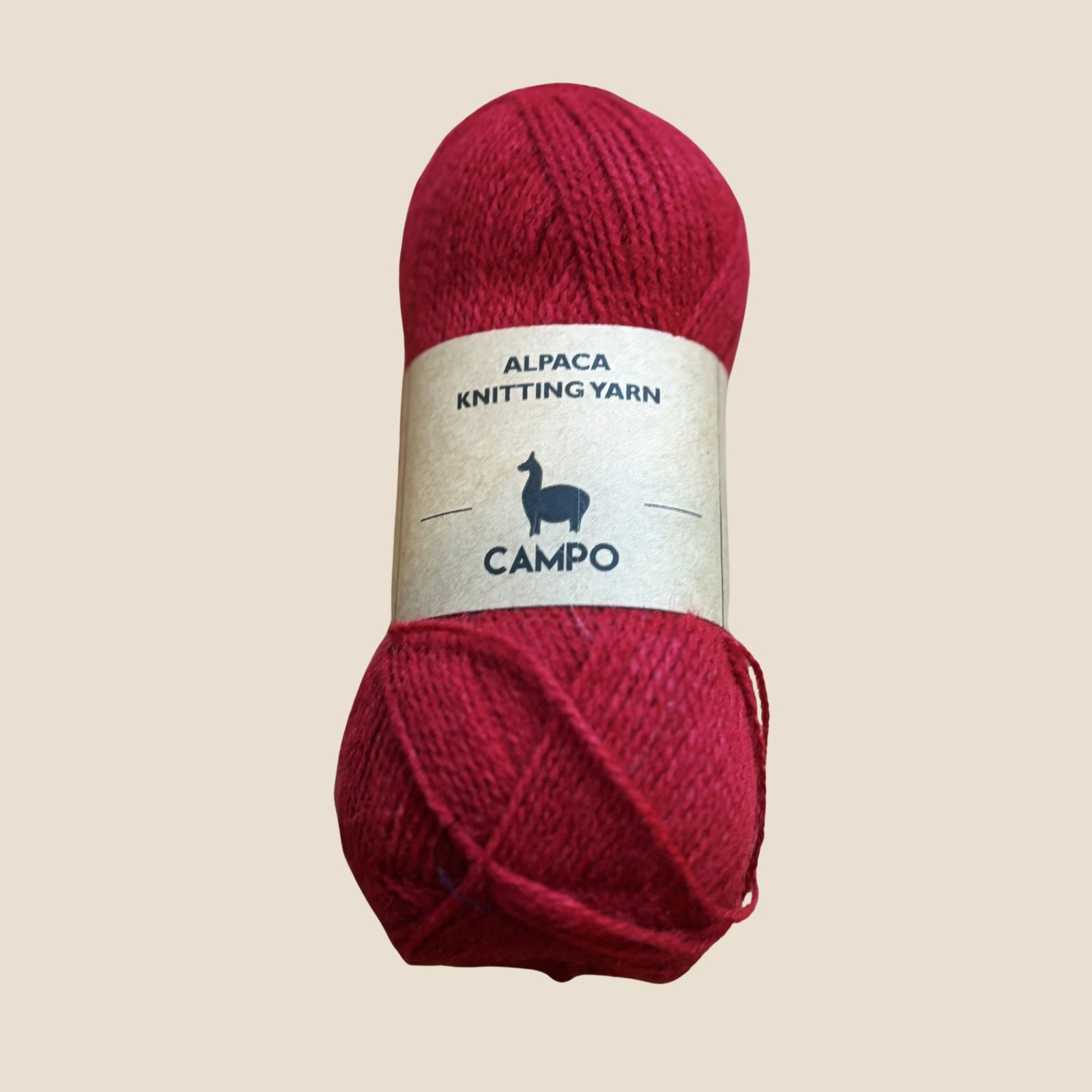 Red alpaca knitting yarn with a label on a beige background