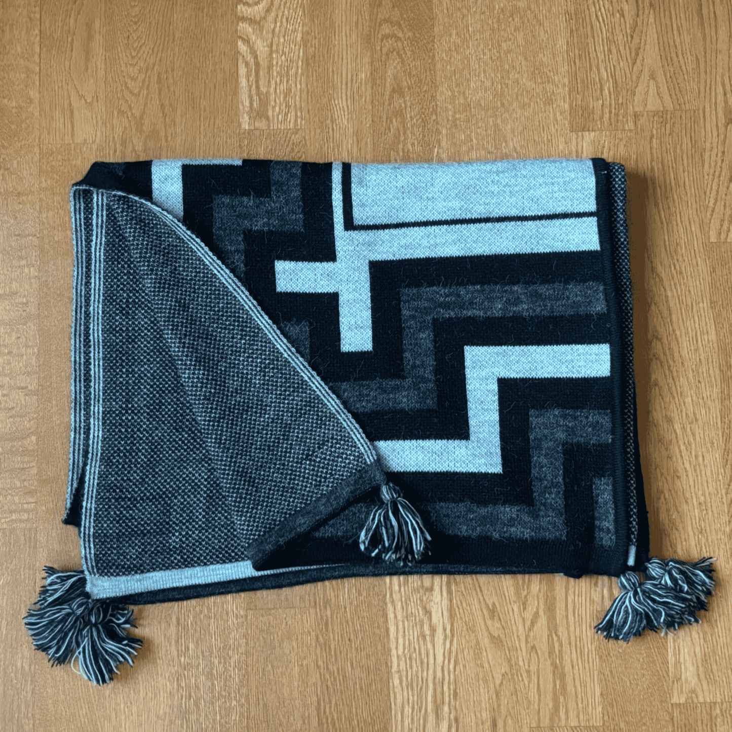 Folded shawl with geometric pattern on a wooden floor