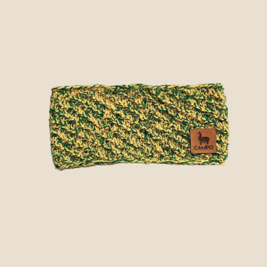 Green and yellow knitted headband with a brown label on a white background