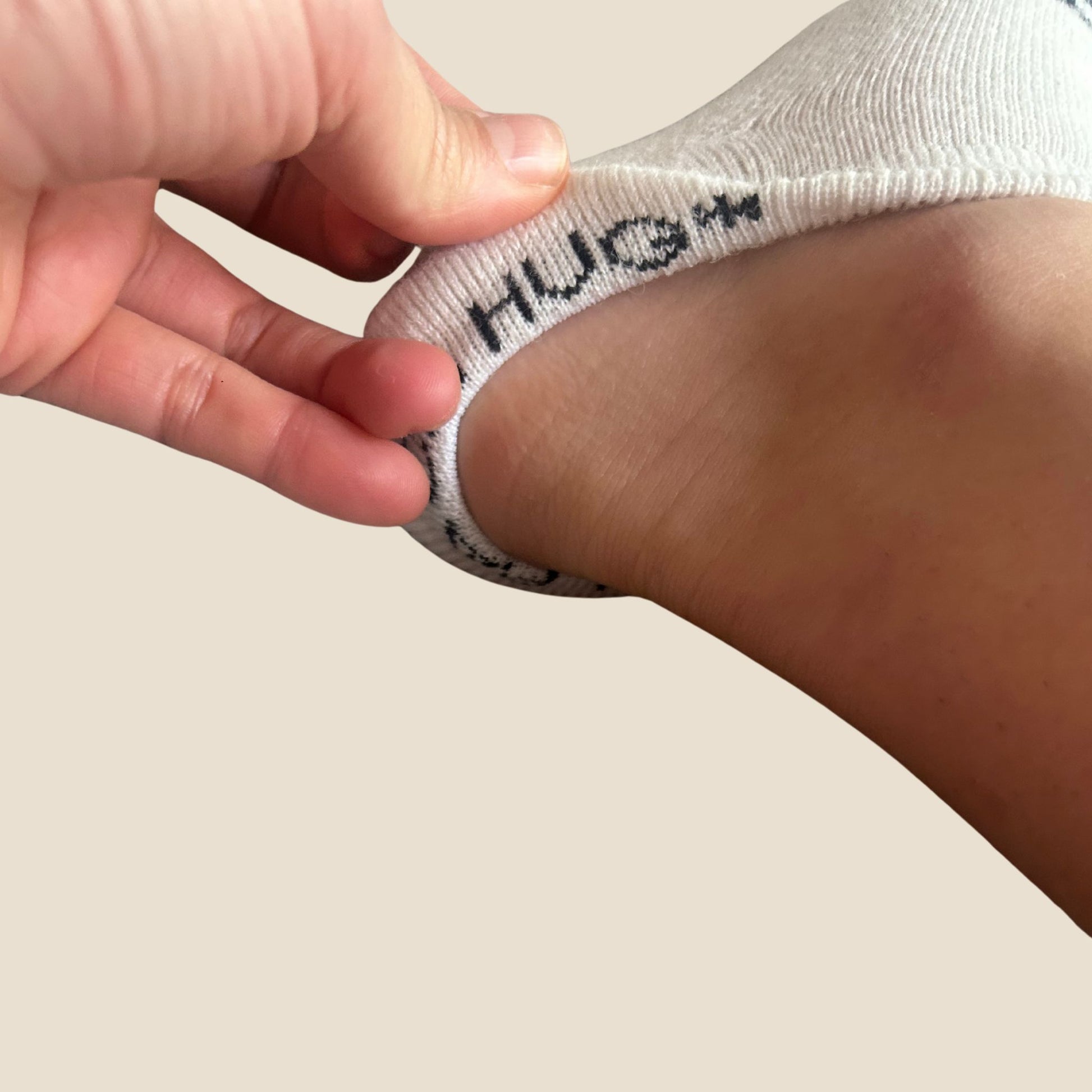 Person wearing a white sock with 'HUG' on a neutral background