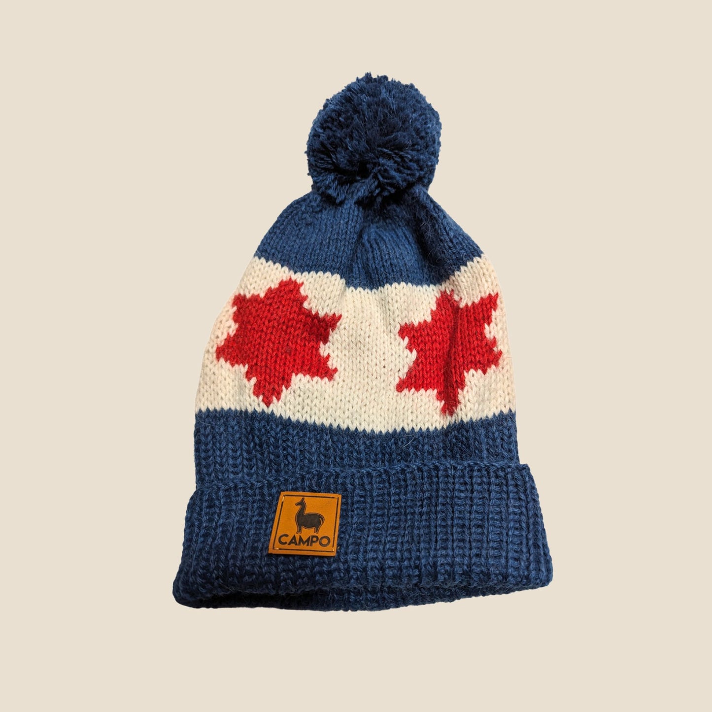 Knitted beanie with red maple leaf design on a beige background