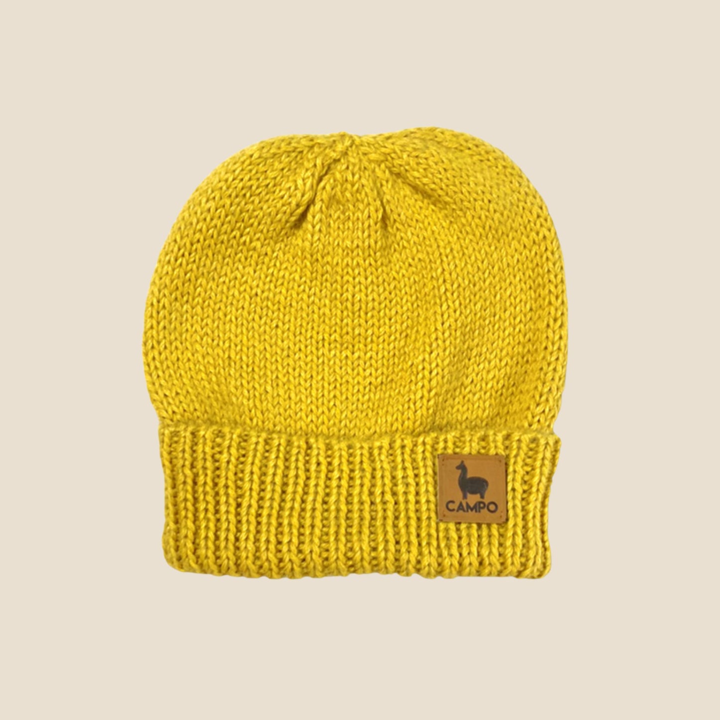 Mustard knit beanie with a Campo logo on a beige background