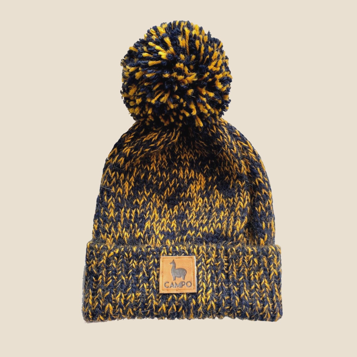 Knitted beanie with pom-pom and Campo logo on a beige background