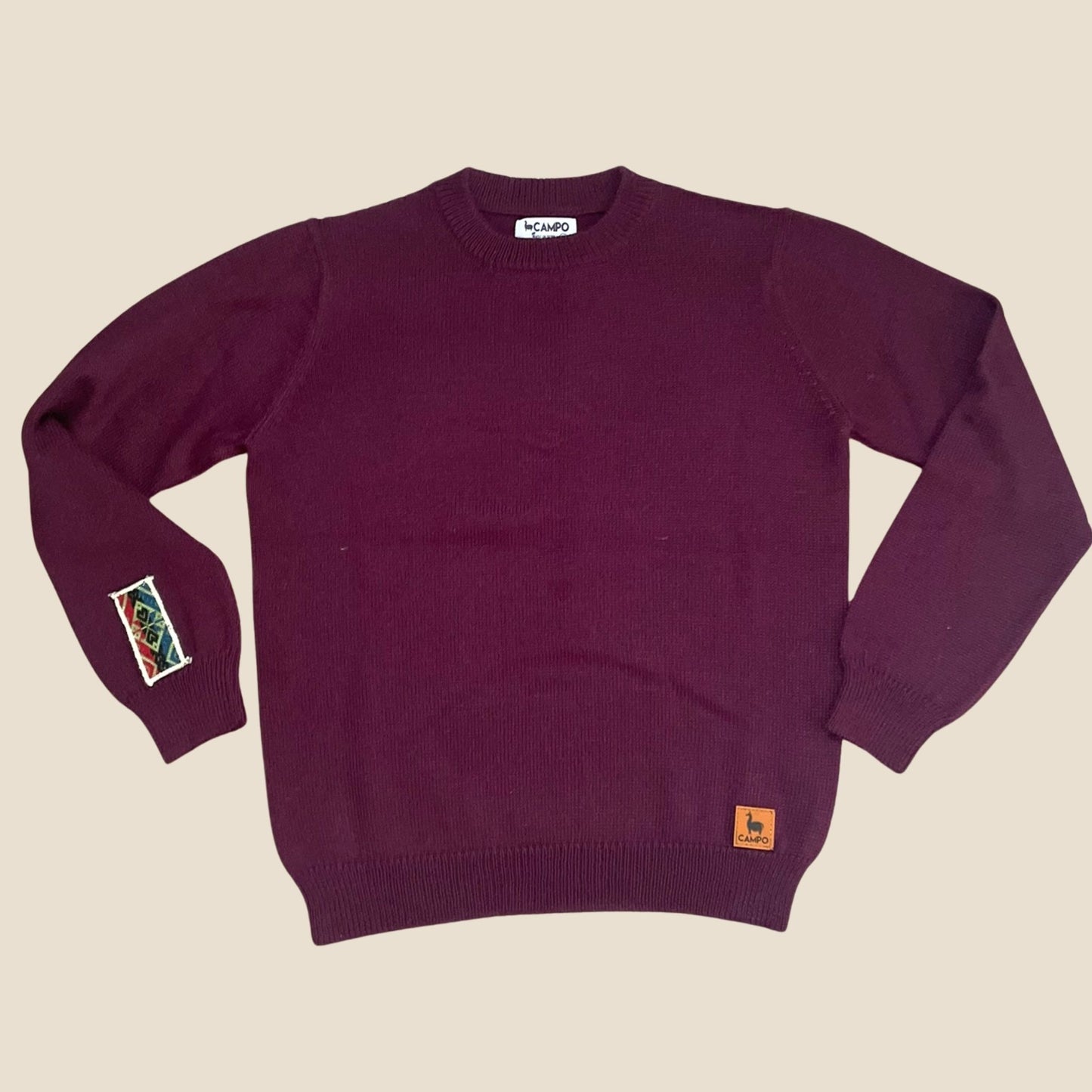 Eggplant sweater with small Campo logos on a beige background