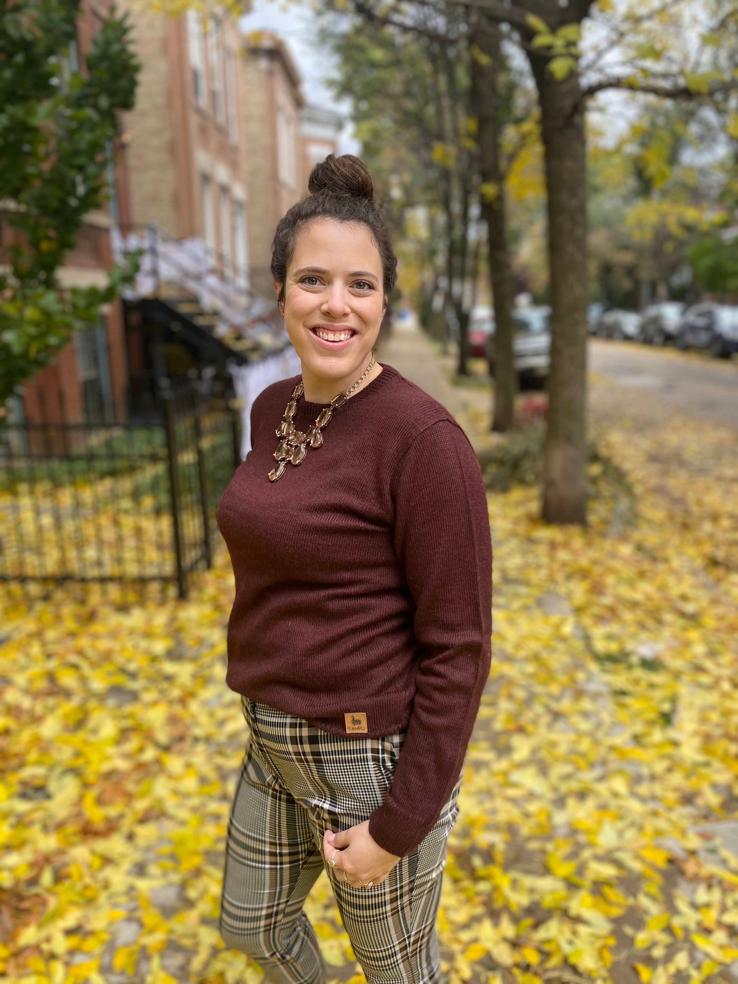 Woman standing on a street with autumn leaves and buildings in the background