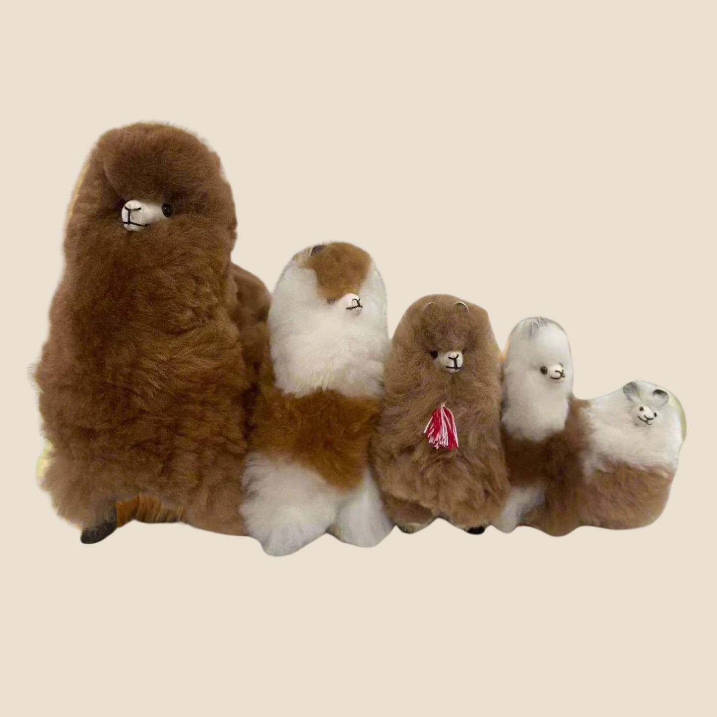 Set of plush alpaca toys in various sizes on a beige background