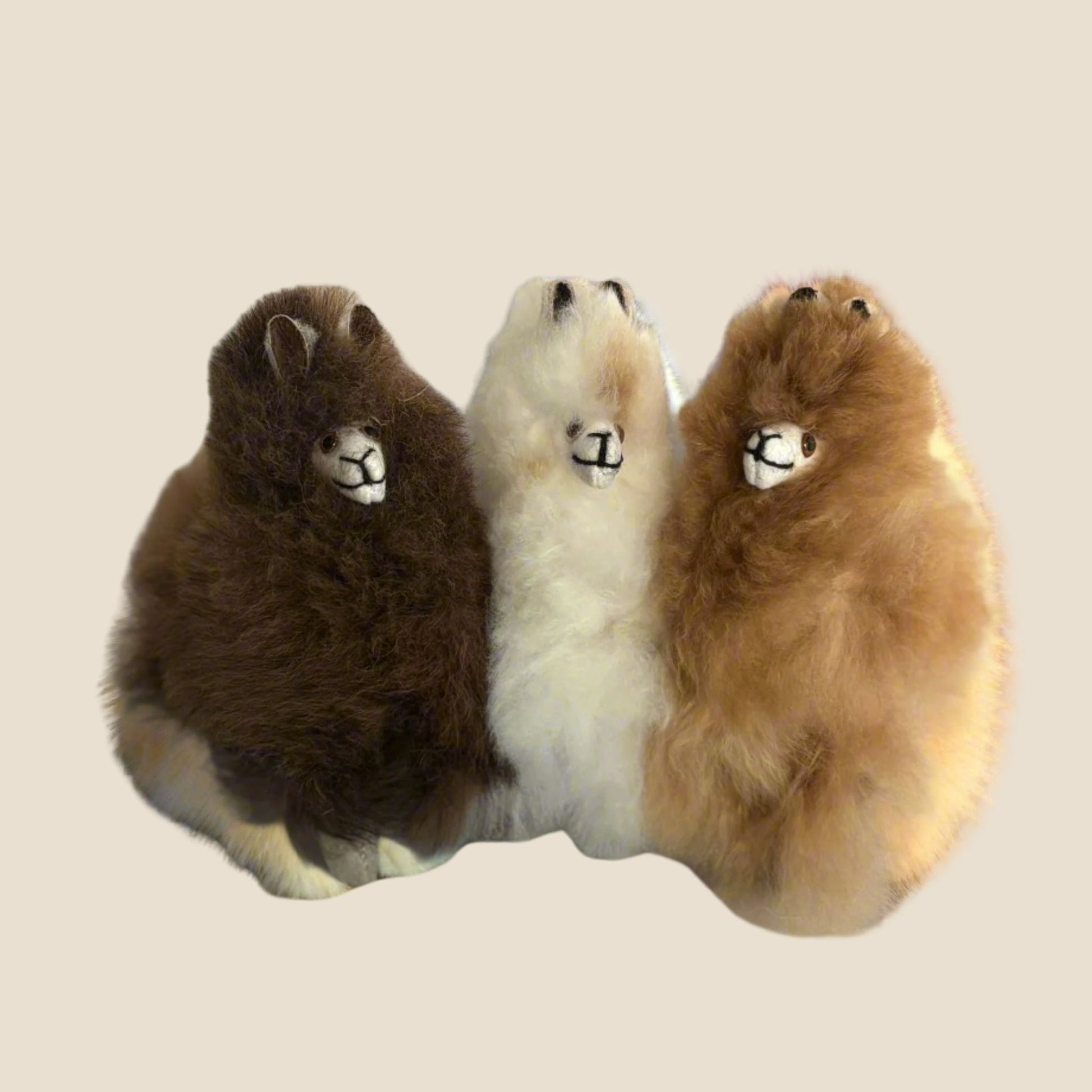Three plush toys alpaca on a beige background