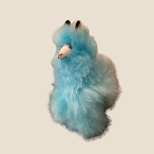 Blue plush alpaca toy on a beige background