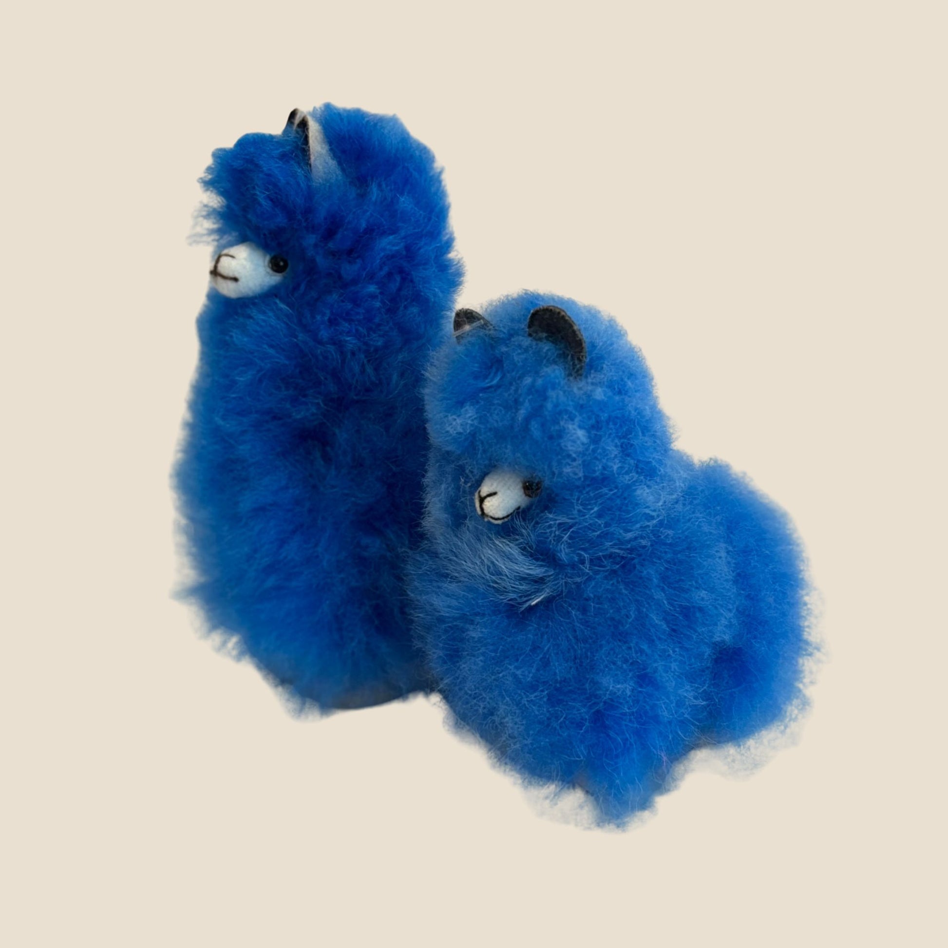 Two blue plush toys alpaca on a beige background