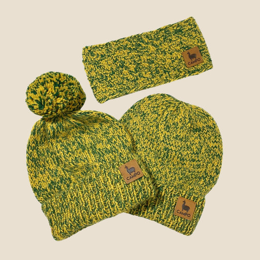 Green and yellow knit hat with pom-pom and matching headband on a beige background