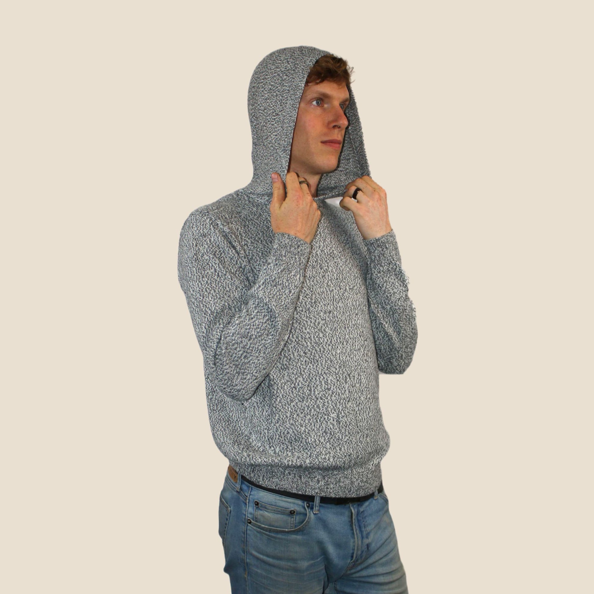 Man wearing a gray hooded sweater against a beige background