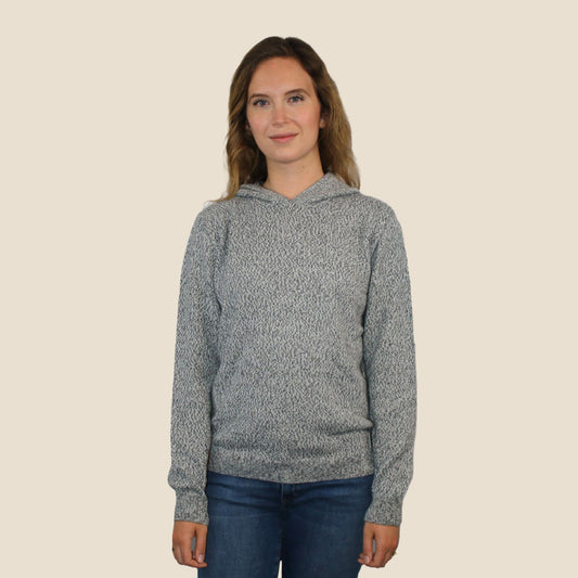 Woman wearing a gray hoodie against a beige background