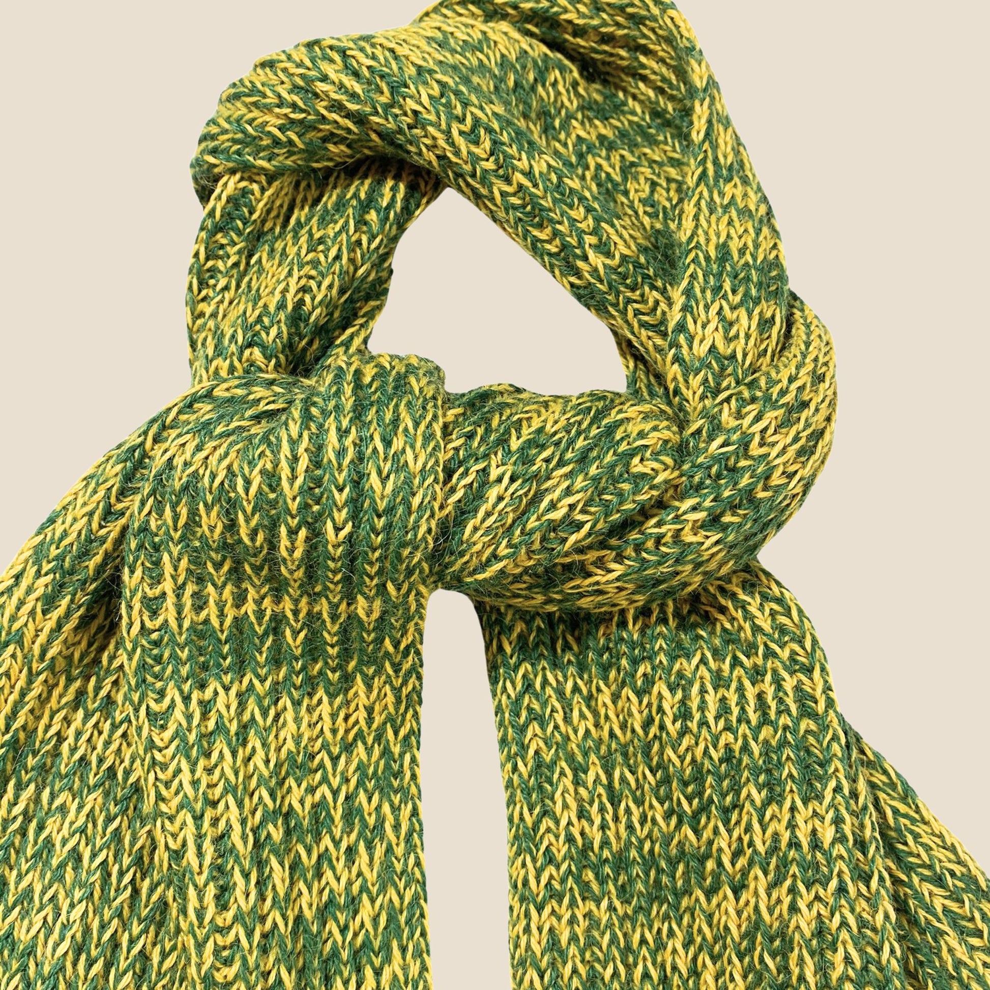 Green and yellow knitted scarf on a beige background