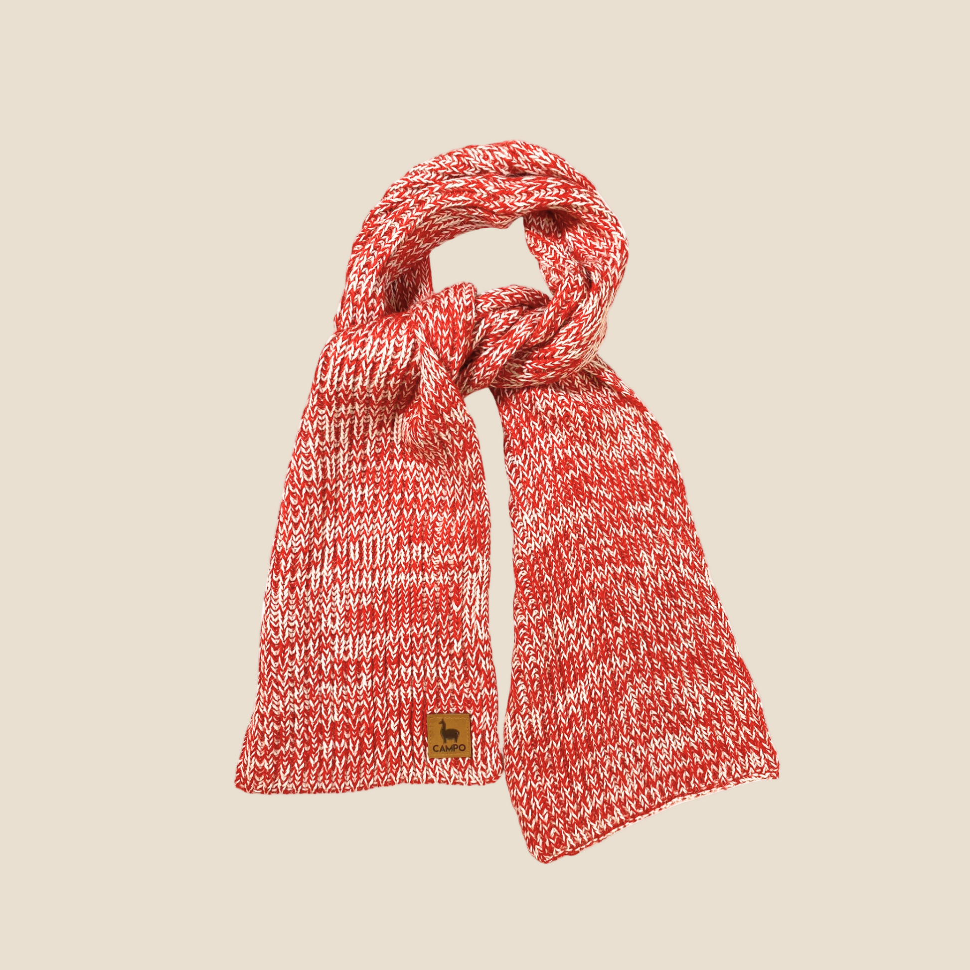 A red and white knitted scarf draped on a plain background.
