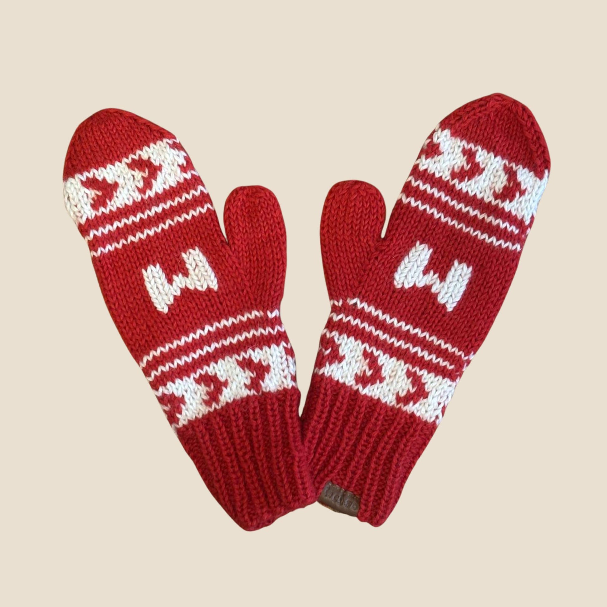 Red knitted mittens with white pattern on a beige background