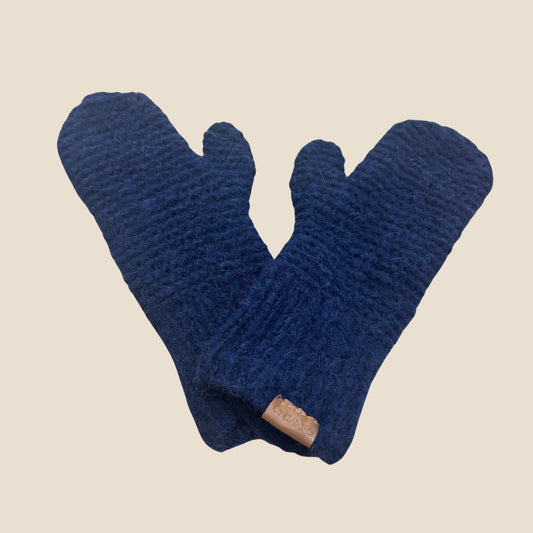 Pair of dark blue knit mittens with a brown label on a beige background