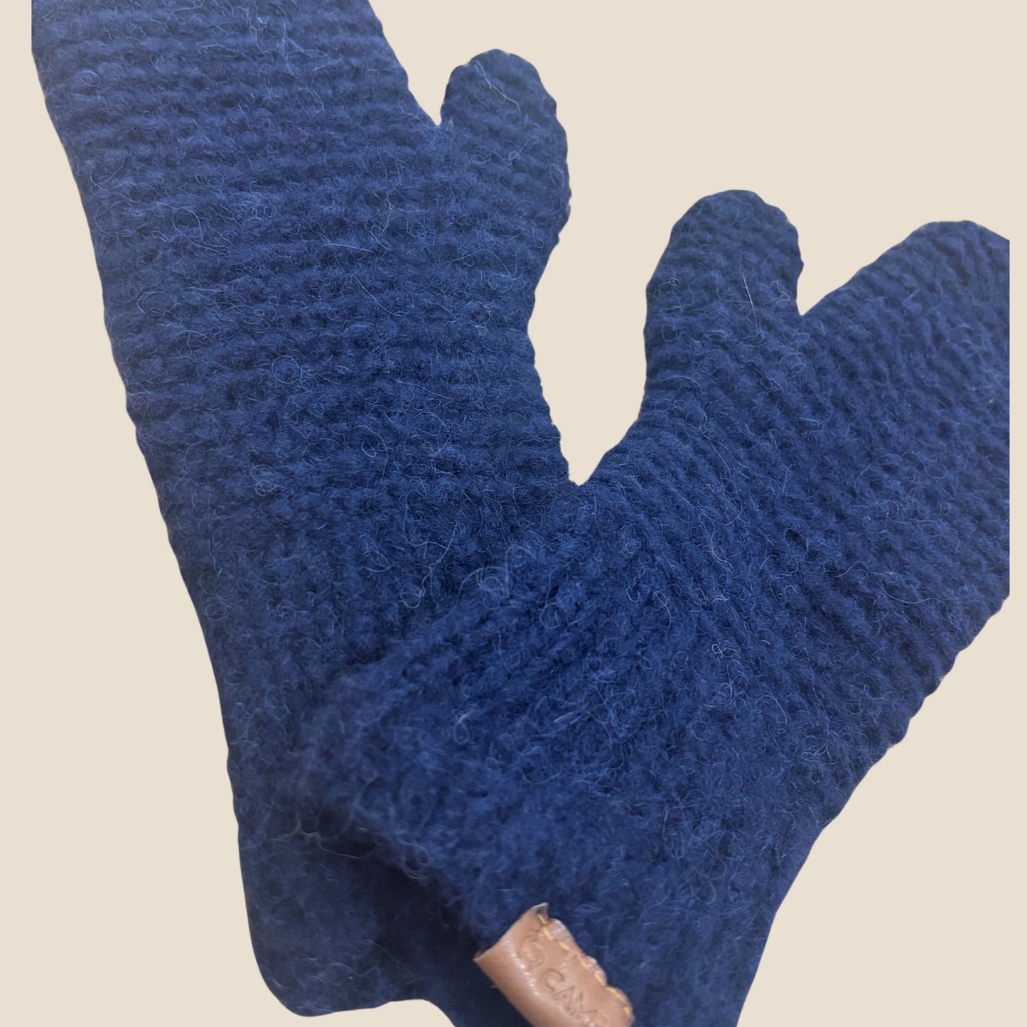 Dark blue knitted mittens  on a beige background