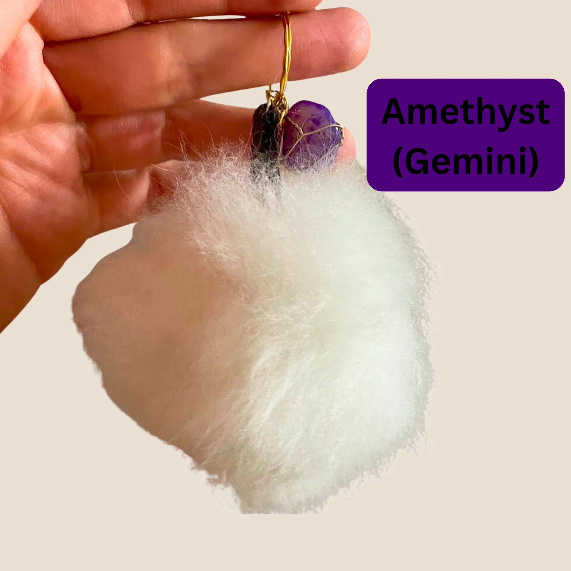 Hand holding a purple gemstone keychain labeled 'Amethyst (Gemini)' on a white background.