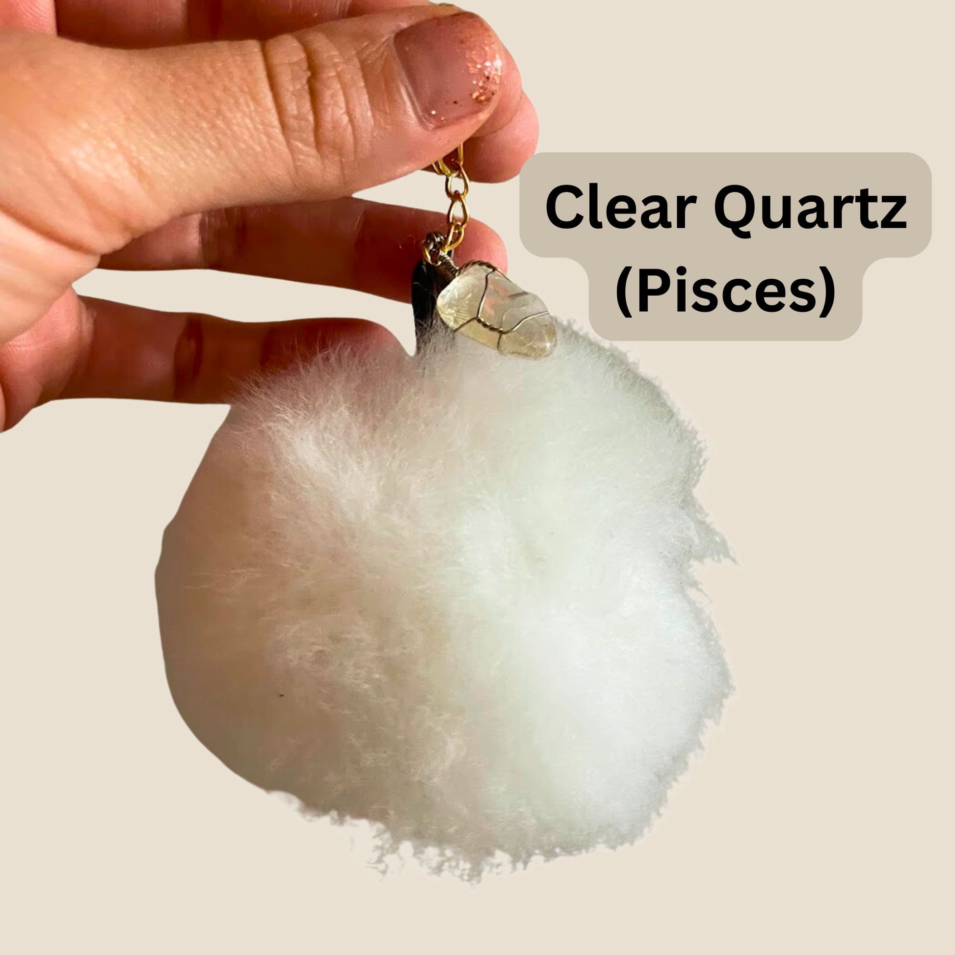 Clear Quartz crystal with a hand holding it against a plain background