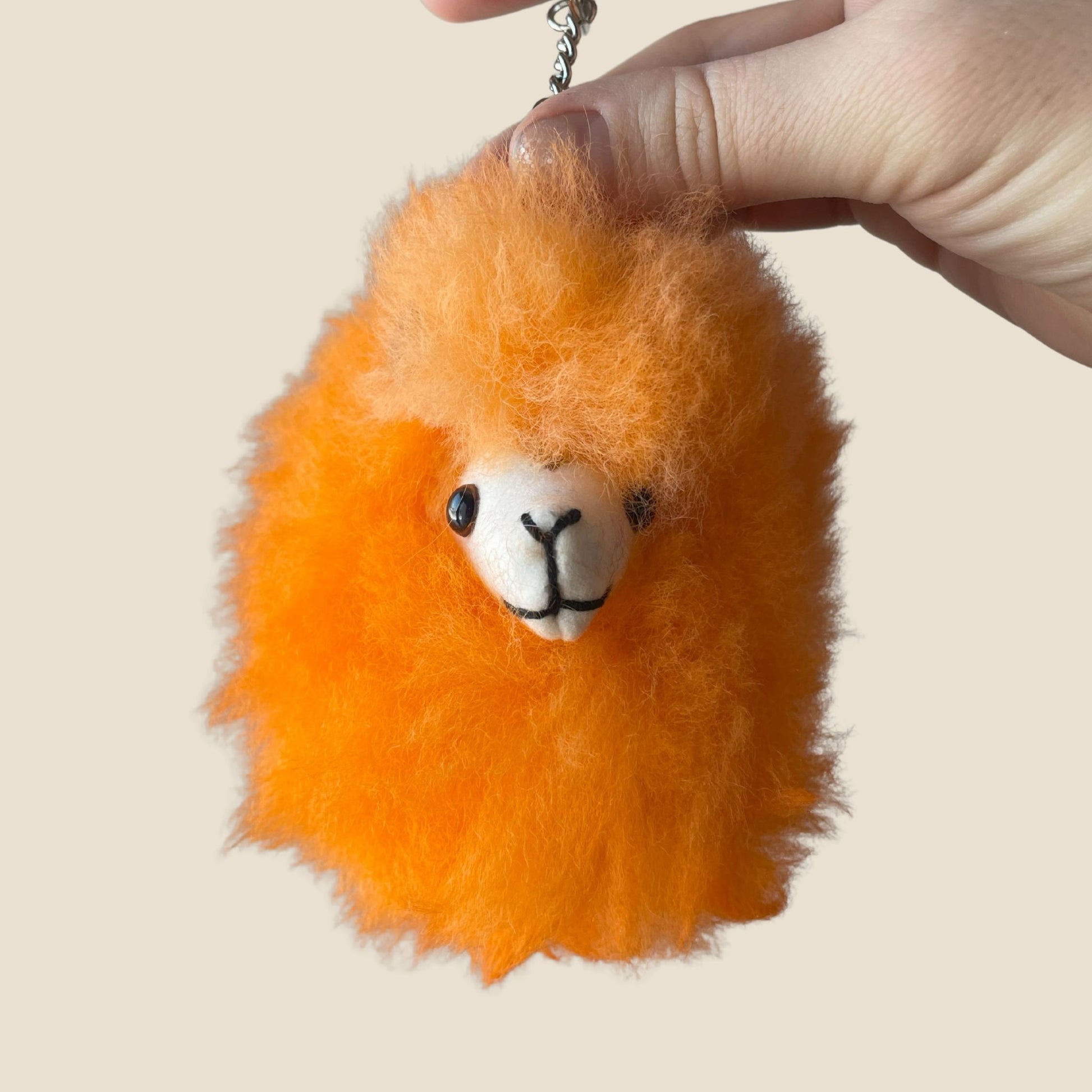 Orange fluffy keychain with a face on a beige background