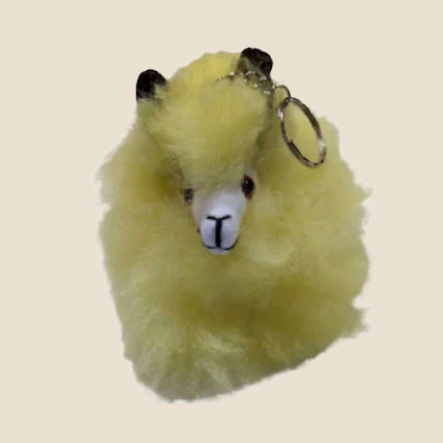 Yellow fluffy keychain with a face on a beige background