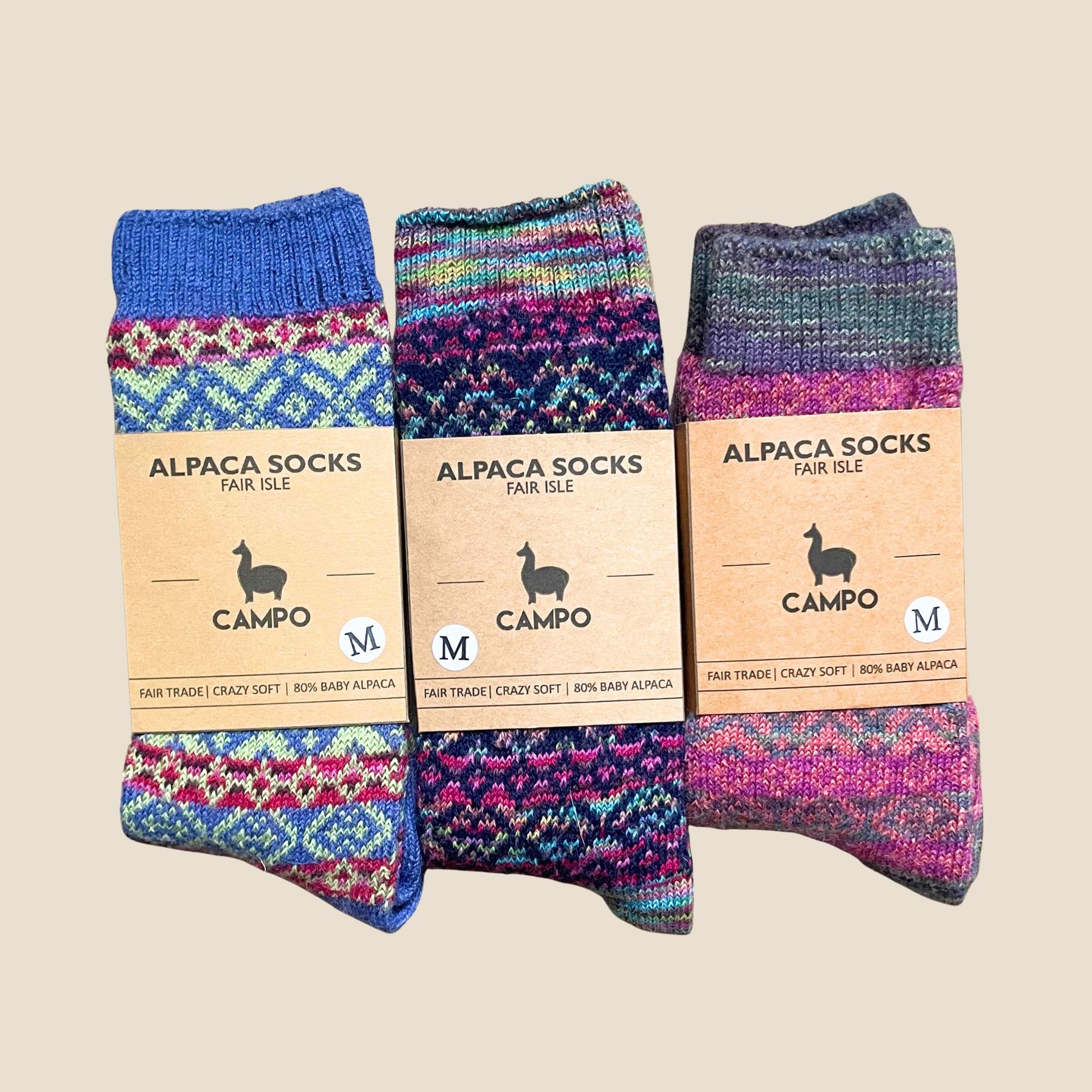 Three pairs of colorful alpaca socks with matching labels on a beige background