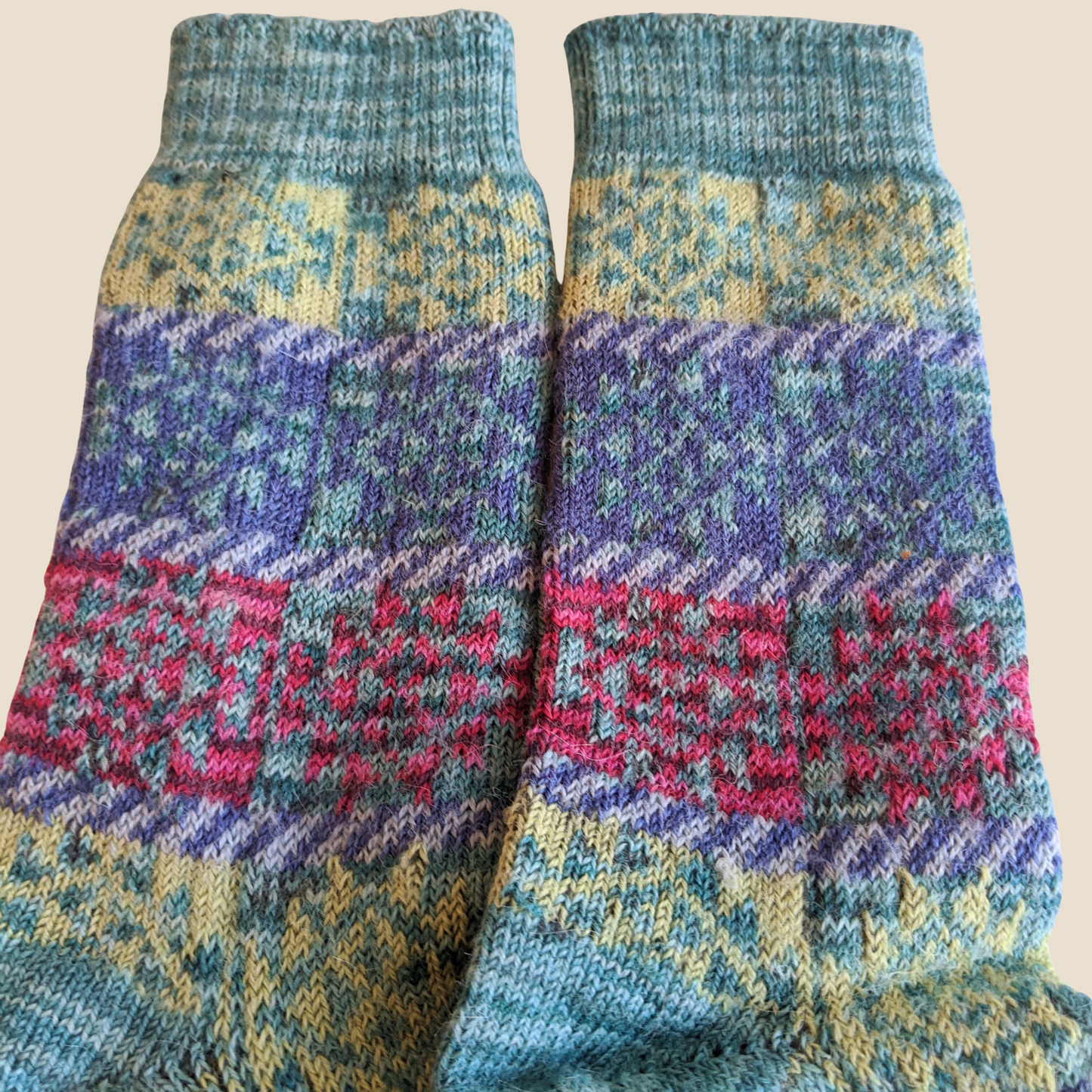 Pair of colorful knitted socks with a pattern on a beige background