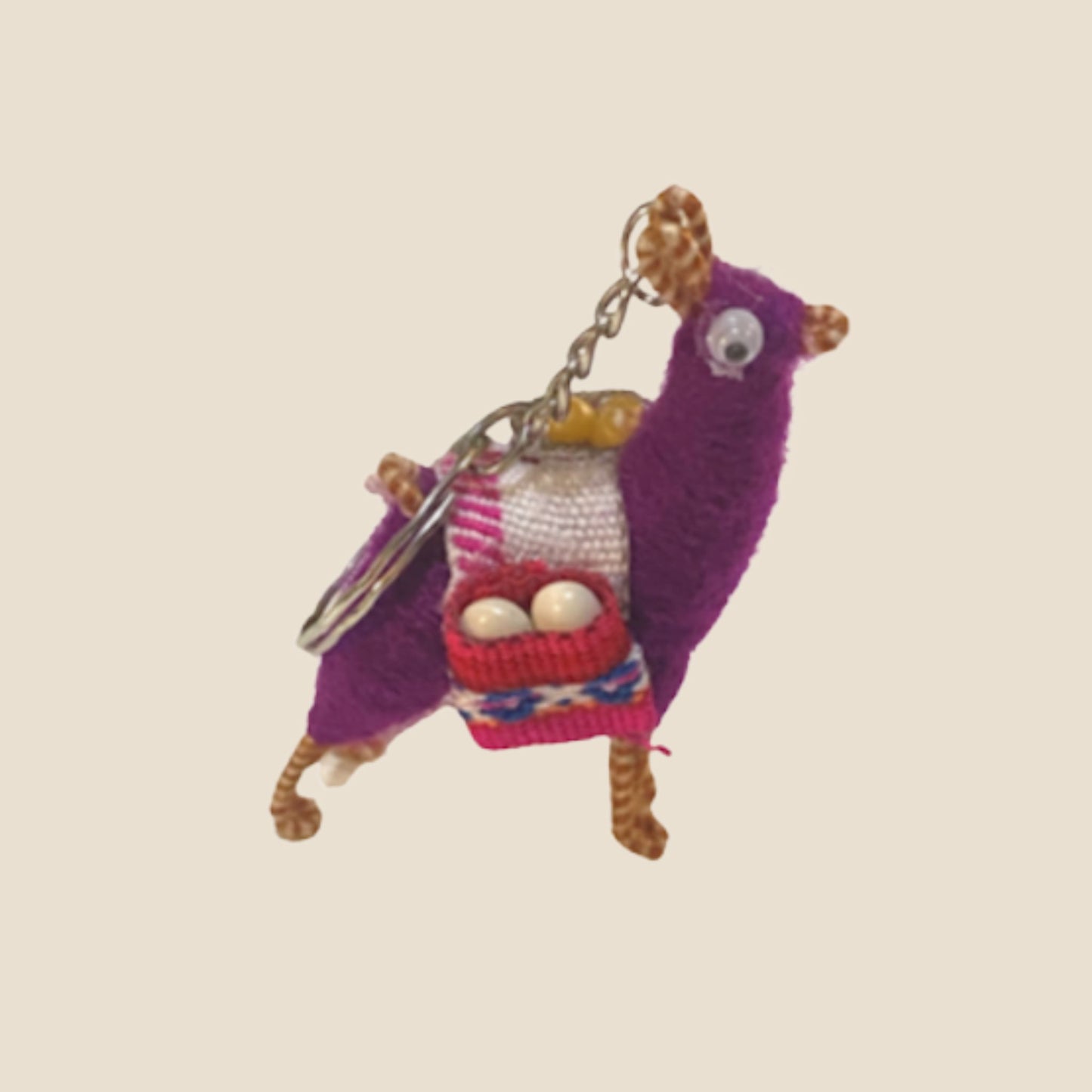 Purple alpaca keychain with a pink bag on a beige background