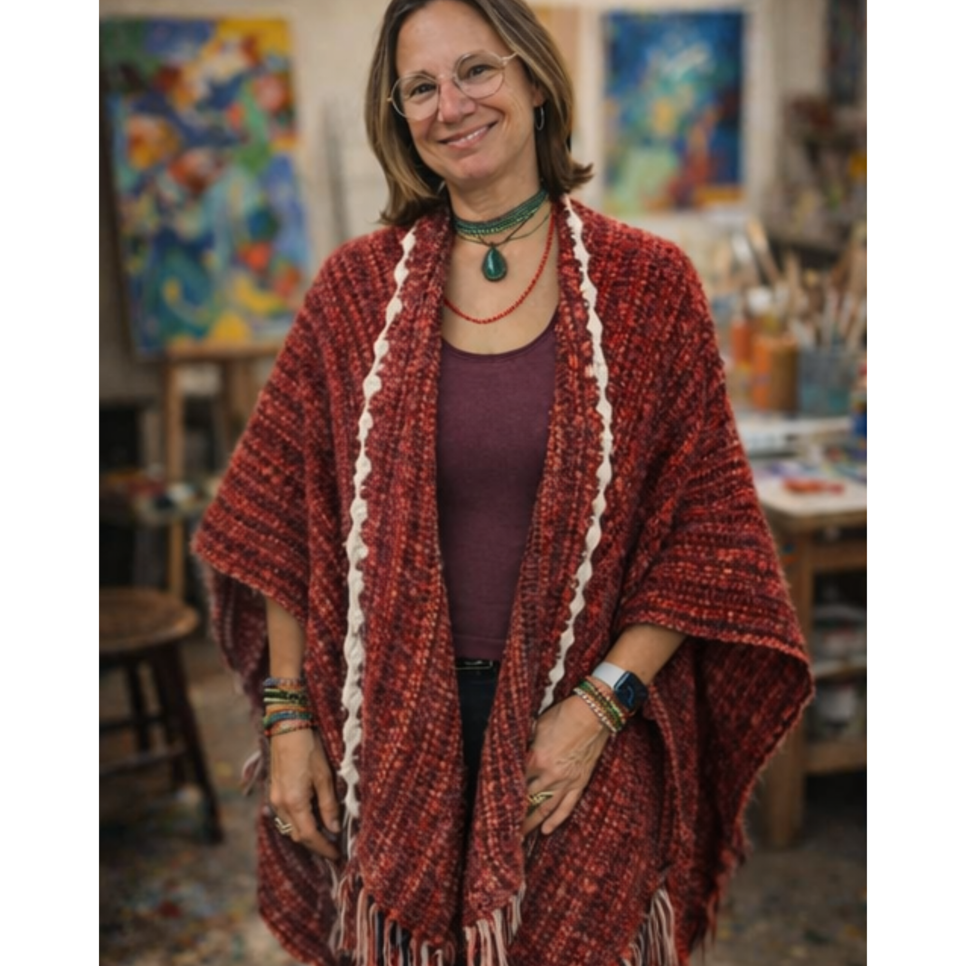 Woman wearing a red shawl in an art studio with colorful paintings in the background