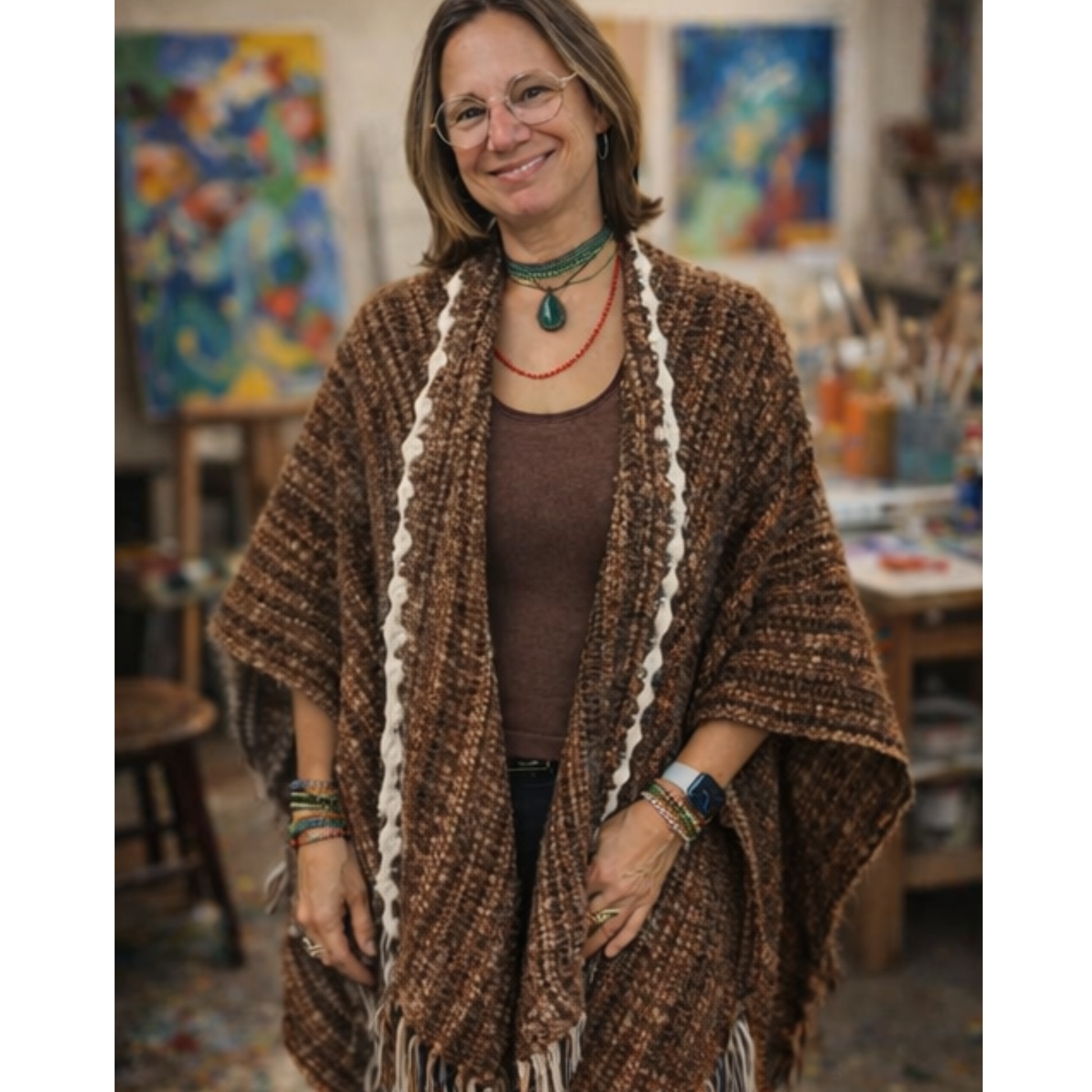 Woman wearing a brown shawl in an art studio with colorful paintings in the background