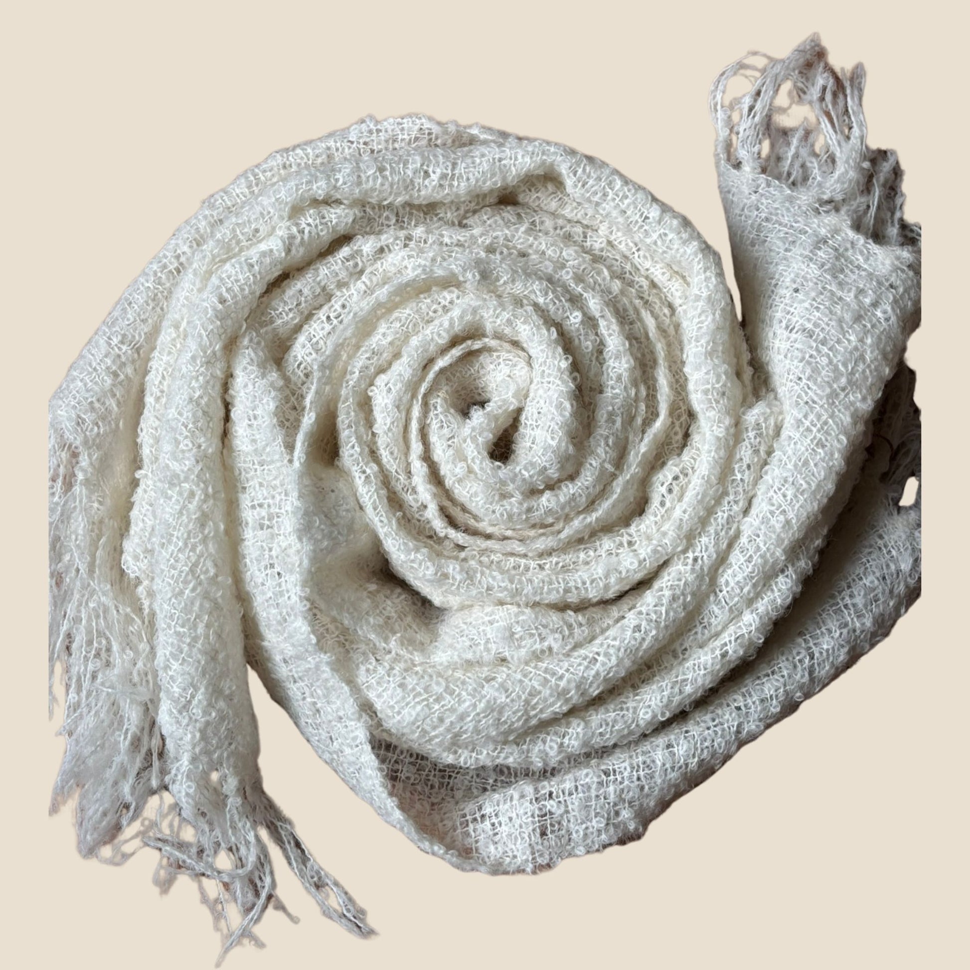 Rolled-up beige scarf with tassels on a beige background