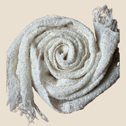 Rolled-up beige scarf with tassels on a beige background