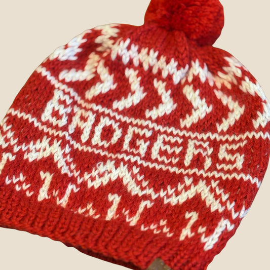 Red knit beanie with white pattern on a beige background
