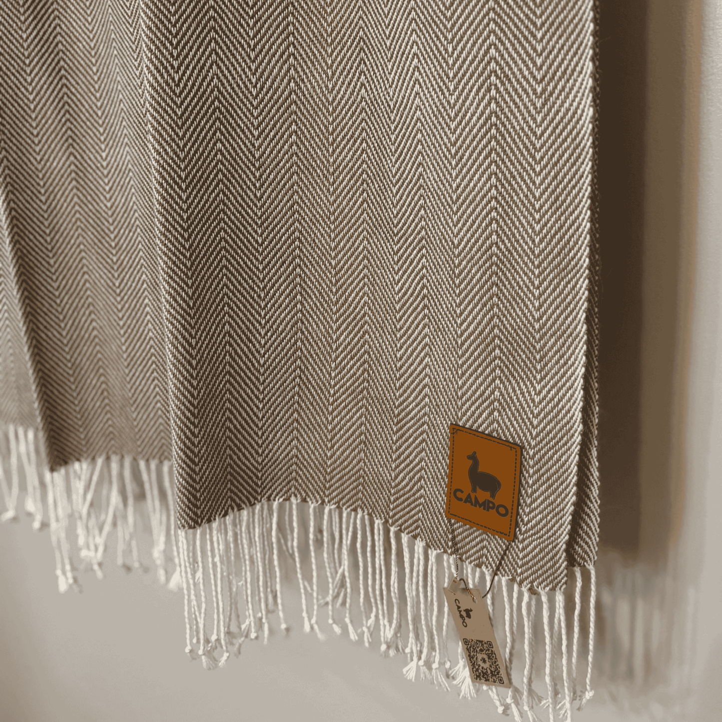 Textured fabric with fringes and a brand tag on a neutral background