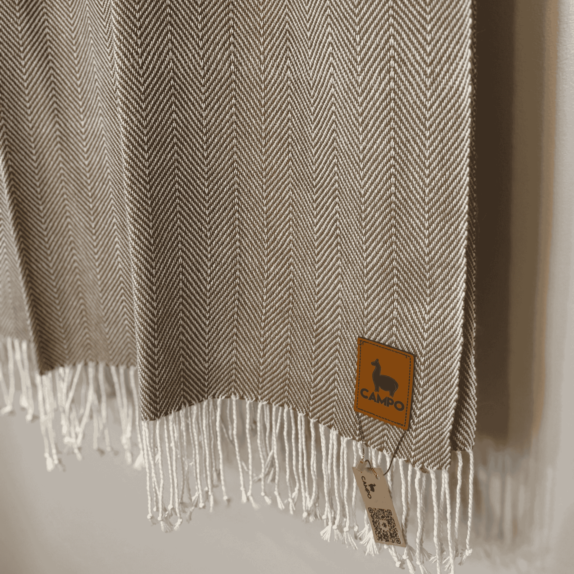 Textured fabric with fringes and a brand tag on a neutral background