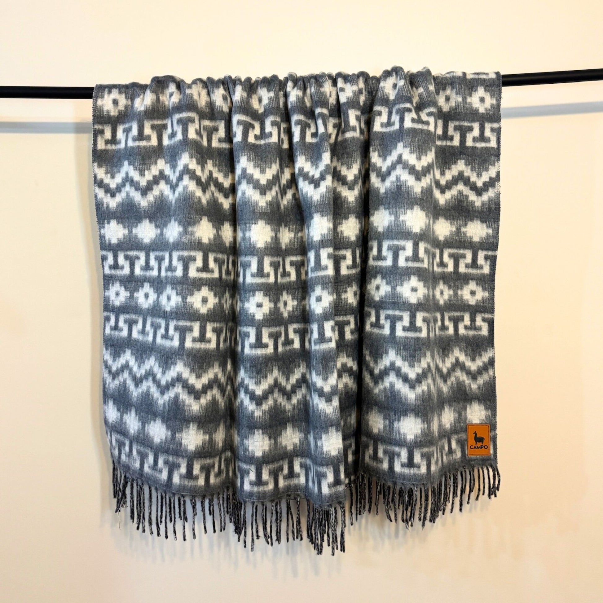 Silver and white patterned scarf with fringes on a beige background