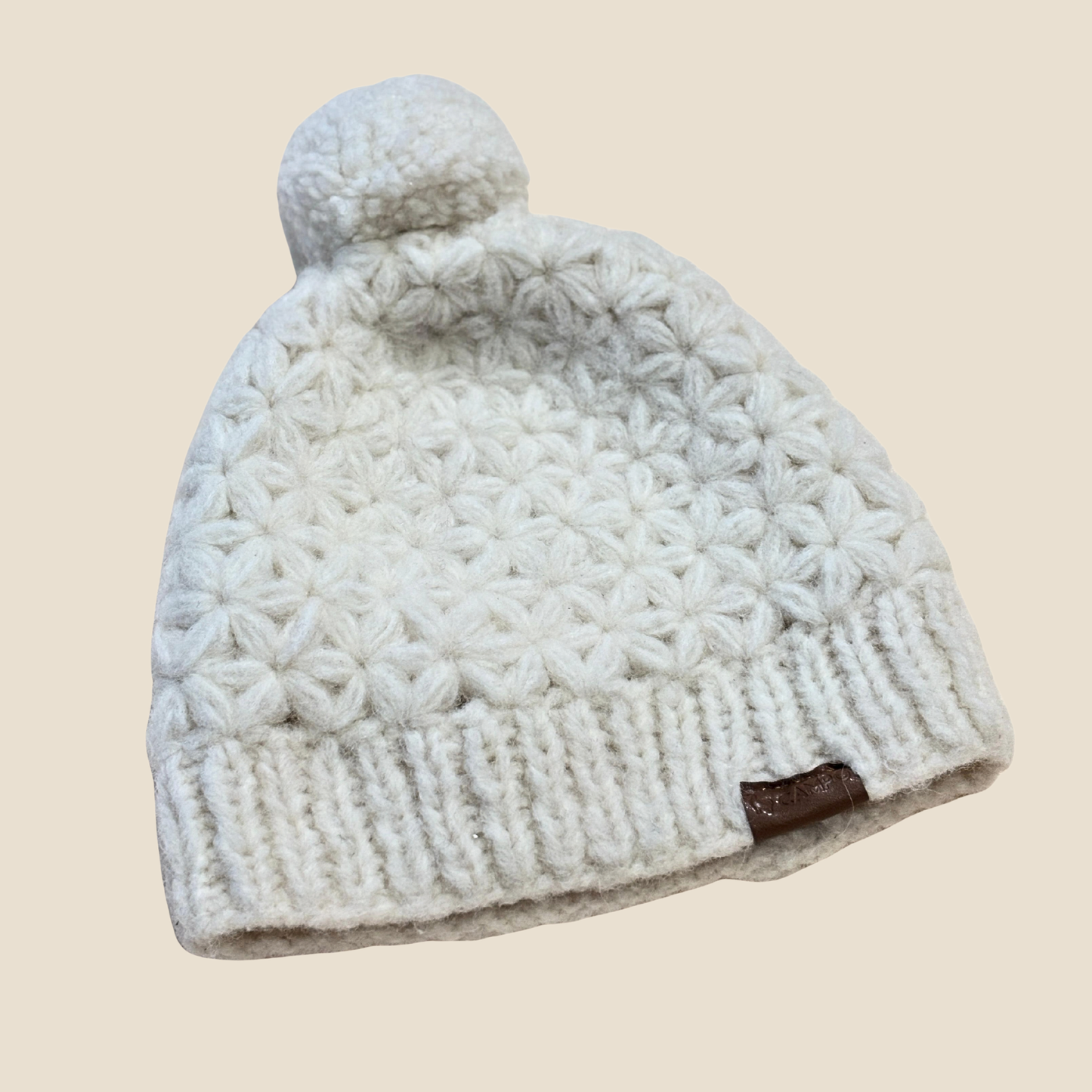 Knitted beanie with pom-pom on a beige background