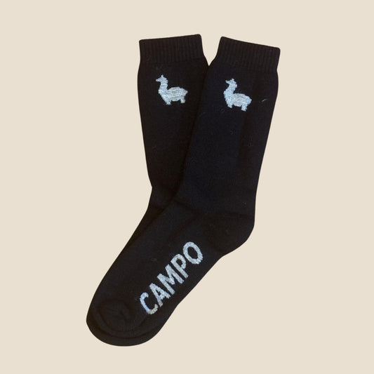 Black socks with white alpaca designs and 'CAMPO' branding on a beige background