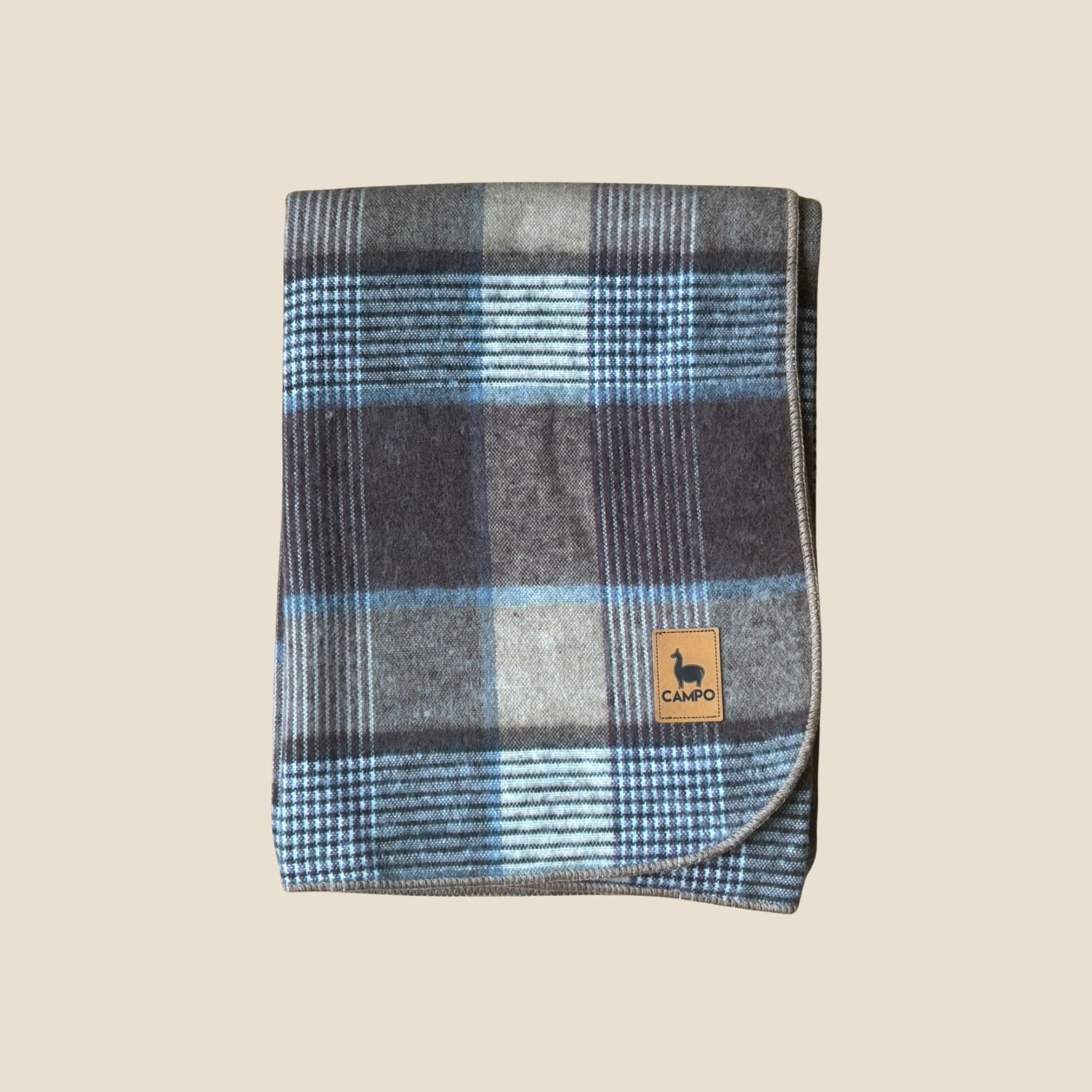 Plaid blanket with a brand logo on a beige background