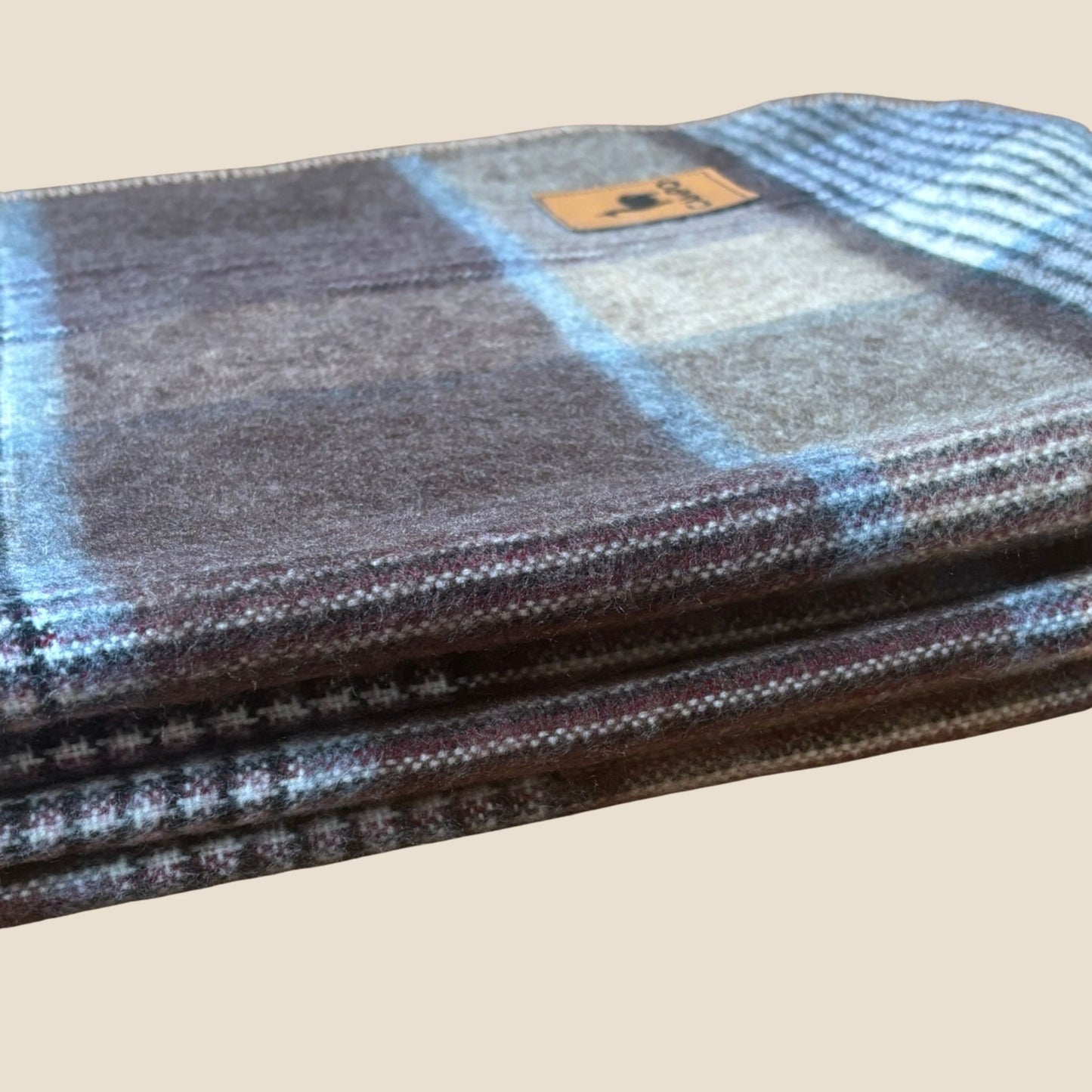 Plaid-patterned fabric roll with a visible brand logo on a beige background