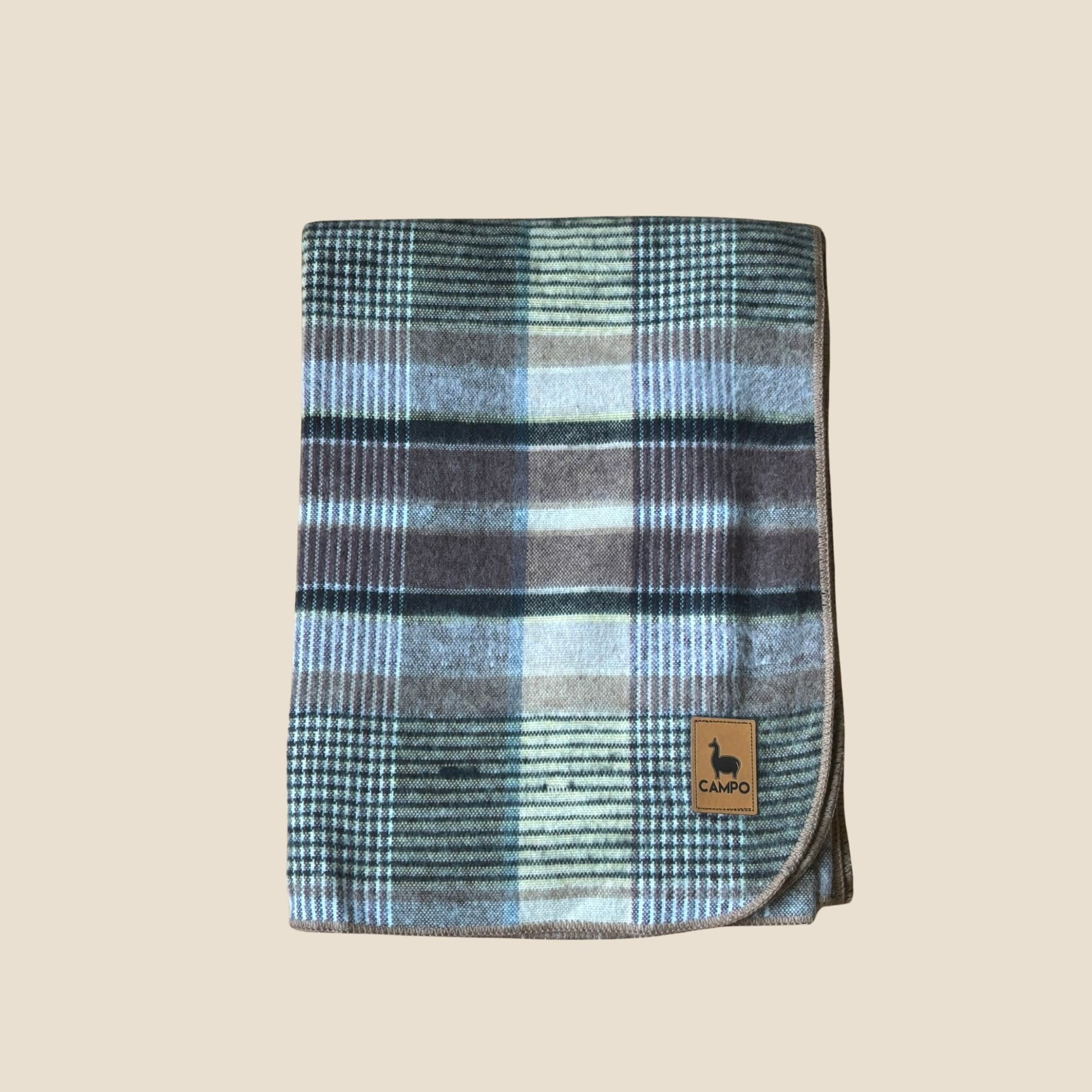 Plaid blanket with a brand logo on a beige background