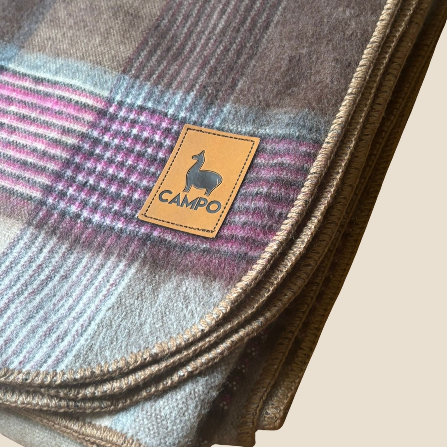 Plaid blanket with 'Campo' brand label on a beige background