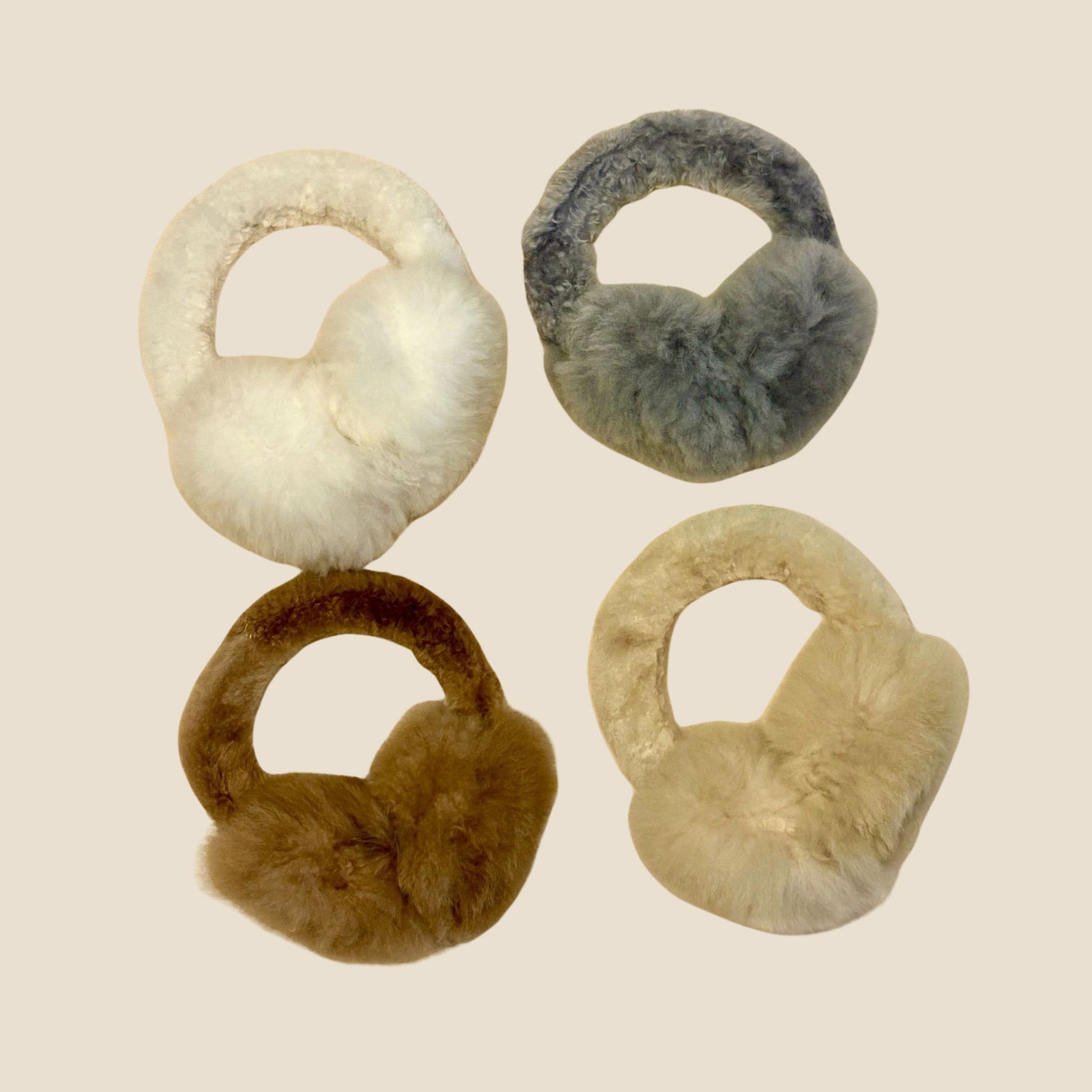 Four pairs of fur ear muffs in different colors on a beige background