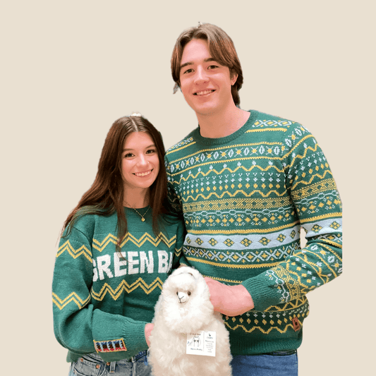Two people wearing green patterned sweaters with a Alpaca on a beige background