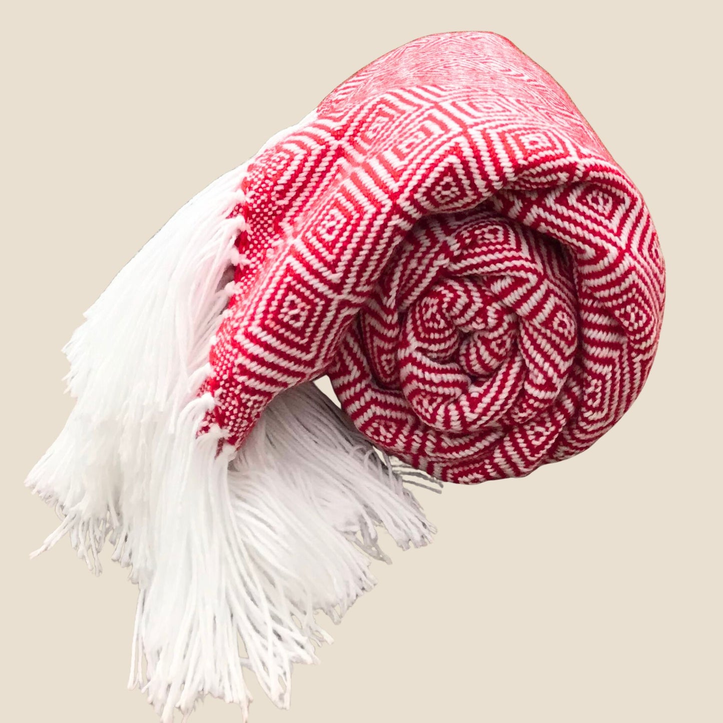 Red and white patterned blanket with fringes on a beige background