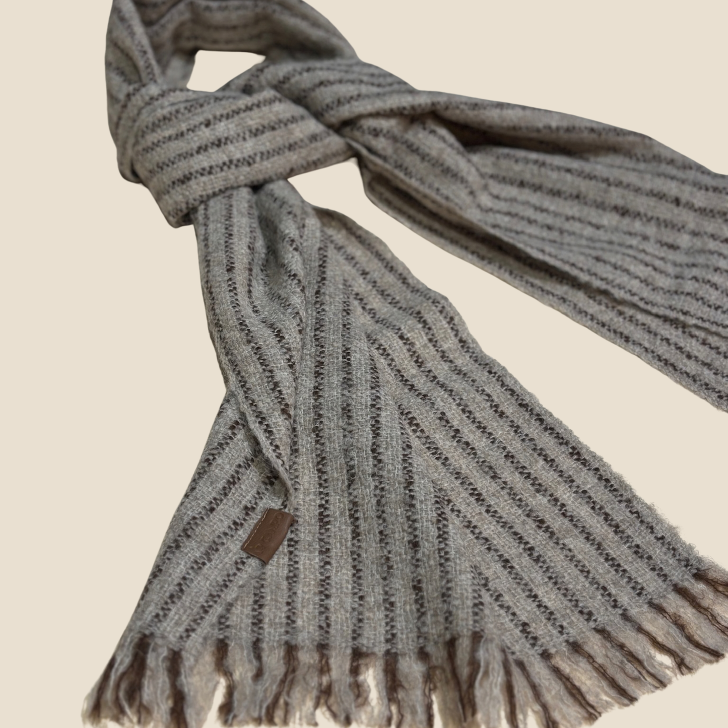 Gray knitted scarf with fringes on a beige background