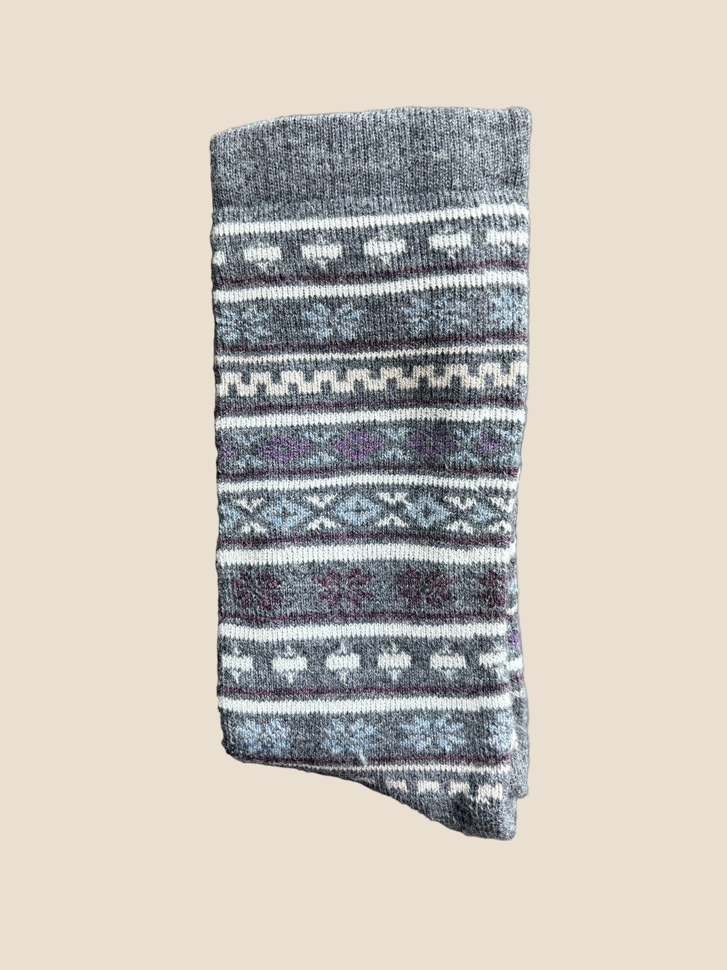 Folded gray sock with white patterns on a dark wooden surface